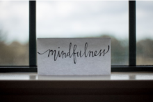 A postcard with the word &quot;mindfulness&quot; sits in front of a window.