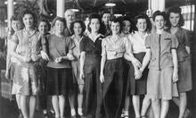 Young women working in a factory pose for a photo.
