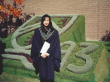 Winnie Leung stands in front of University of Waterloo topiary displaying the shield and the year 1993.