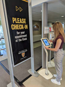 A person interacts with the electronic Campus Wellness kiosk.