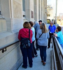 Jane's Walk participants examine a stone facade as part of the Kitchener Rocks tour.