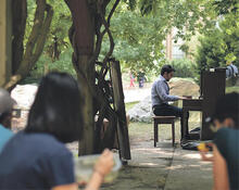 A student plays an outdoor piano on the University campus.