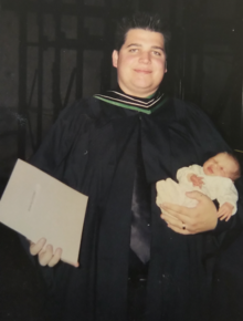 Brandon Sweet in 2002 with his master's degree in one hand and his infant daughter in the other.