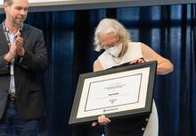 Dean Jean Andrey holds up an framed award.