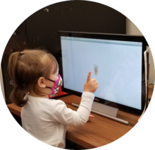 A young girl interacts with a touchscreen.