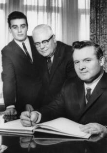 University of Waterloo President Gerry Hagey and alumni representative Peter Barnes look on as Minister of University Affairs Bill Davis signs the official University of Waterloo guestbook at the grand opening ceremony of ESC and B1, March 1965.