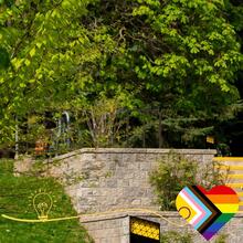 A shot of campus with a progress pride heart sign on a frame.