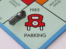 The free parking space on a Monopoly game board with the car playing piece parked on it.