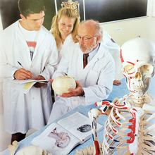 Professor Donald Ranney helps students examine an anatomical skeleton.