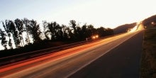 Blurred images of a car's taillights on a curved road.