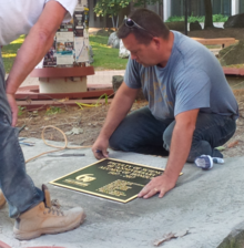 Workers install the alumni plaque in the Peter Russell Rock Garden.