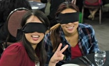 Two dining in the dark participants with their blindfolds flashing a peace sign.