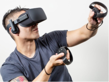 A man wears virtual reality (VR) goggles and handsets.