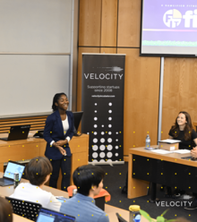 A woman presents her Velocity project to a panel.