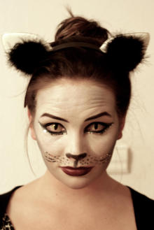 A woman wears cat's eye contact lenses as part of a halloween costume.