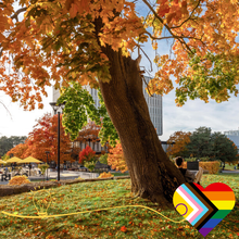 A scene of campus in autumn with a progress pride symbol overlaid.