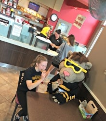 A Warrior volunteer and King Warrior eat Smile Cookies in the SLC Tim Hortons.