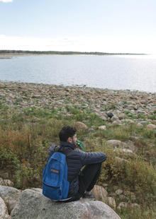 Faisal sits looking at a shoreline.
