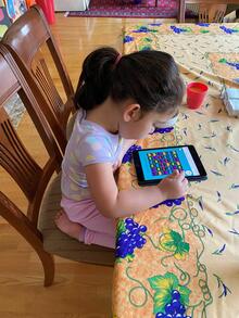 A young girl plays the CARD game on a tablet.