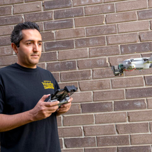 A man uses a remote control to pilot a small drone.