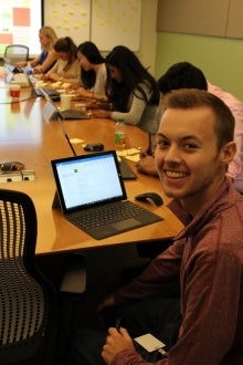 Rhys Hollis smiling from meeting room table