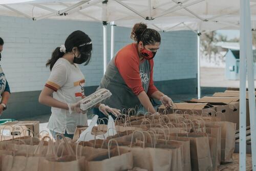 Two volunteers pack items at a food bank.