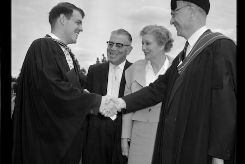 Ron Mullin shakes the hand of Dean of Arts W.K. Thomas as his parents look on.