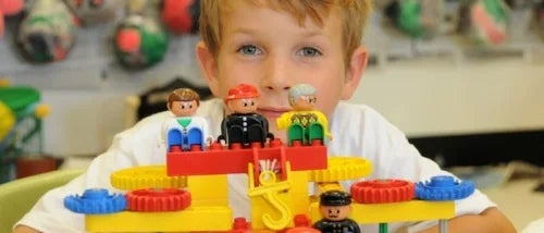 A child sits behind a toy block apparatus.