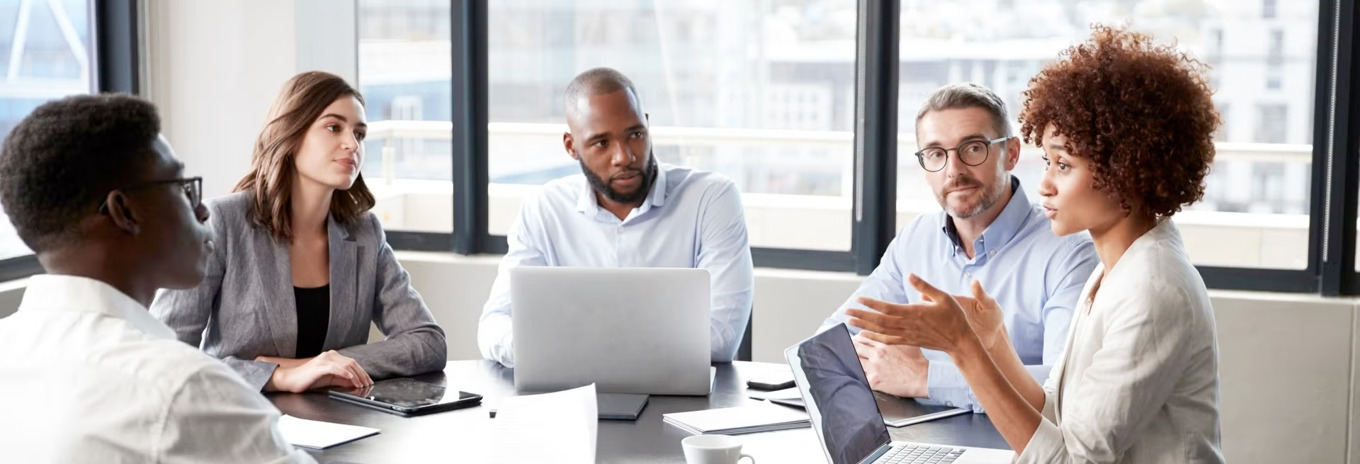 A group of people sit around a meeting table in conversation.