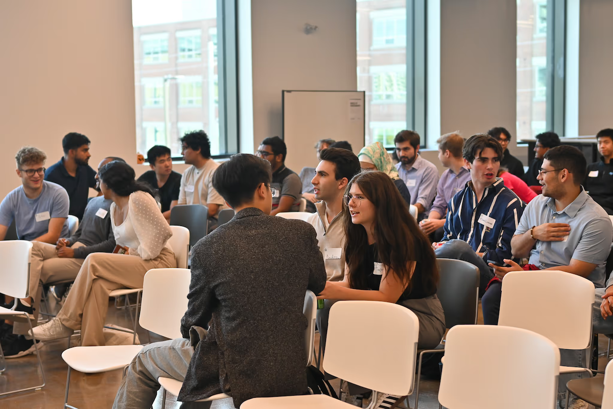 Students wearing nametags sit in chairs at a Velocity event.