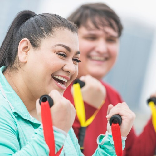 Two people work out with resistance bands.