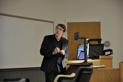 Luke Postle delivering a lecture with an overhead projector.