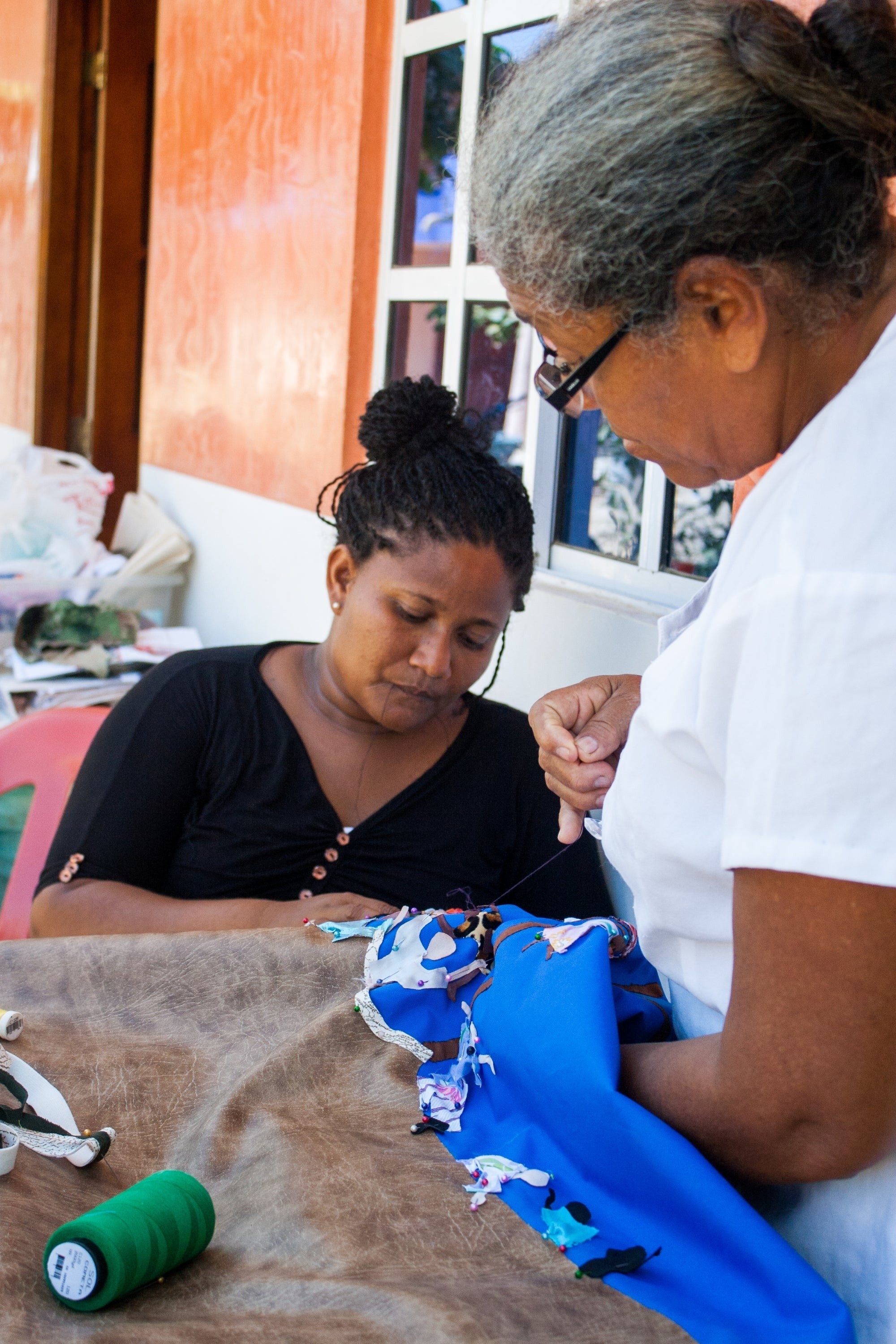 Two women sew a quilt.