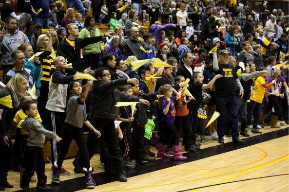 A crowd throws paper airplanes.