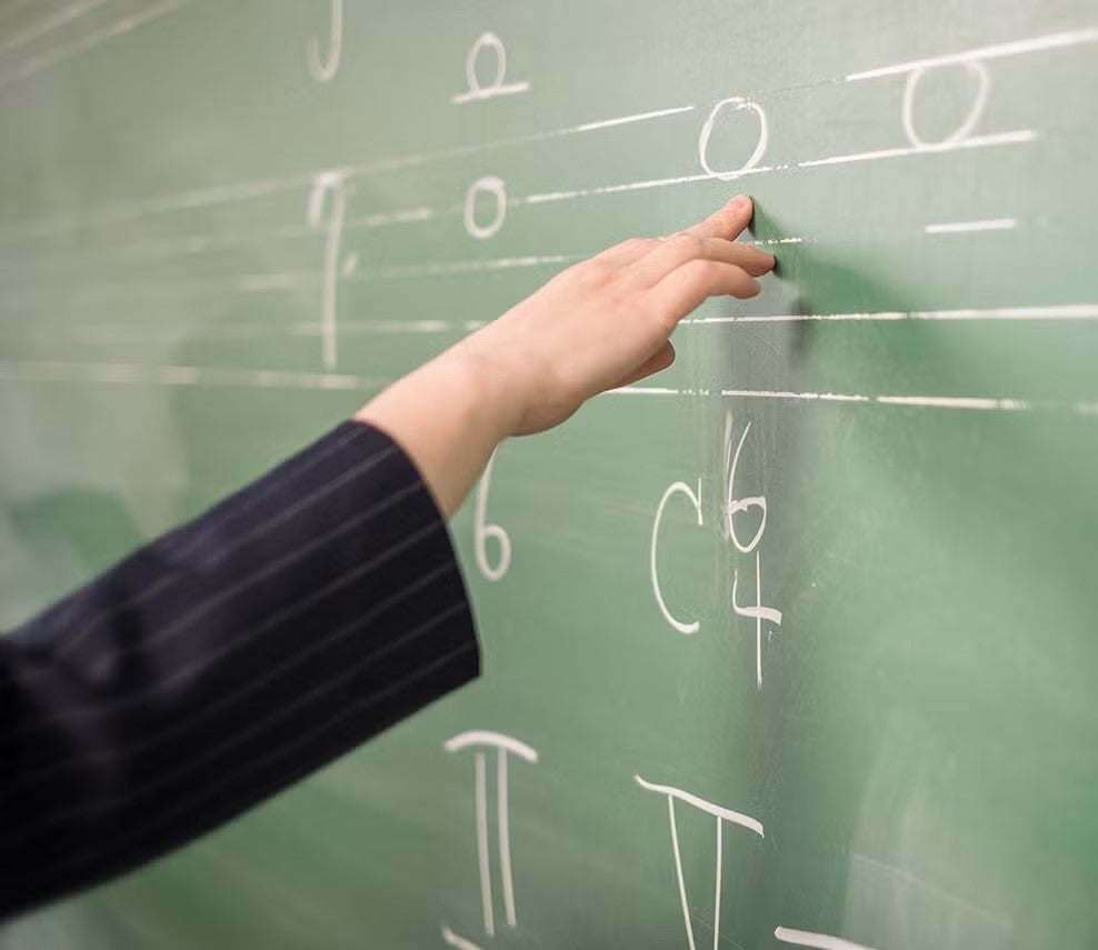 A person writes musical notations on a blackboard.