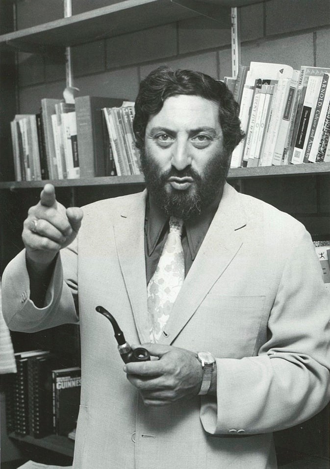 Professor Joseph Gold stands with a pipe in hand in his office circa 1975.