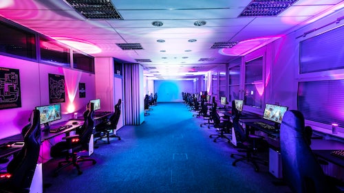 An e-sports playing facility with computer workstations lined up in two rows.