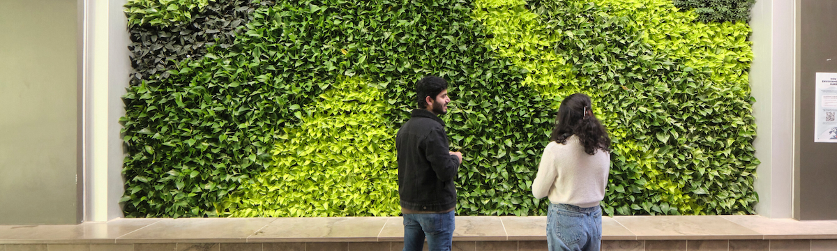 A man and a woman converse in front of a Living Wall.