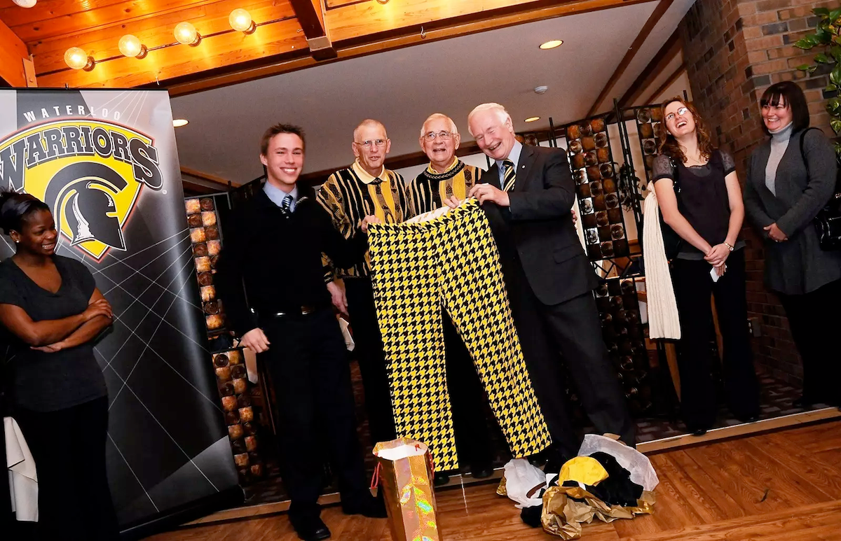 Dave Hollinger and Jack Pearse in matching sweaters holding up checkered golf pants with David Johnston.
