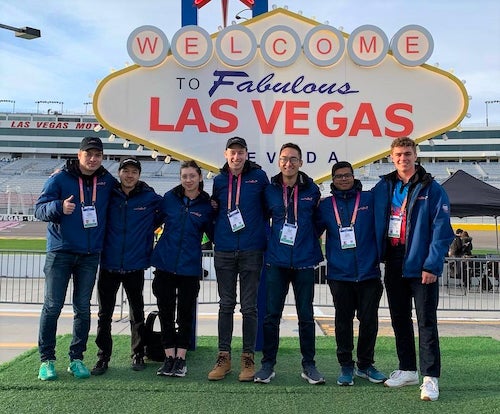 Waterloo team members stand in front of a gaudy Las Vegas speedway sign.