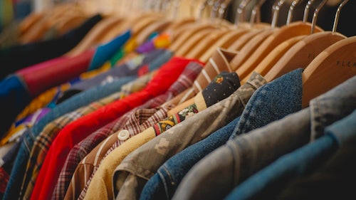 Articles of used clothing on a rack in a thrift store.