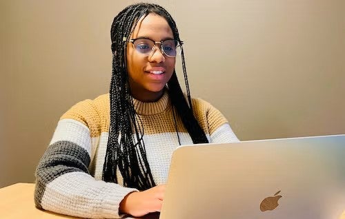 Avonae Gentles sits in front of a laptop.