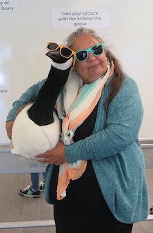 Laurie Strome poses with a plush Canada Goose while wearing sunglasses.