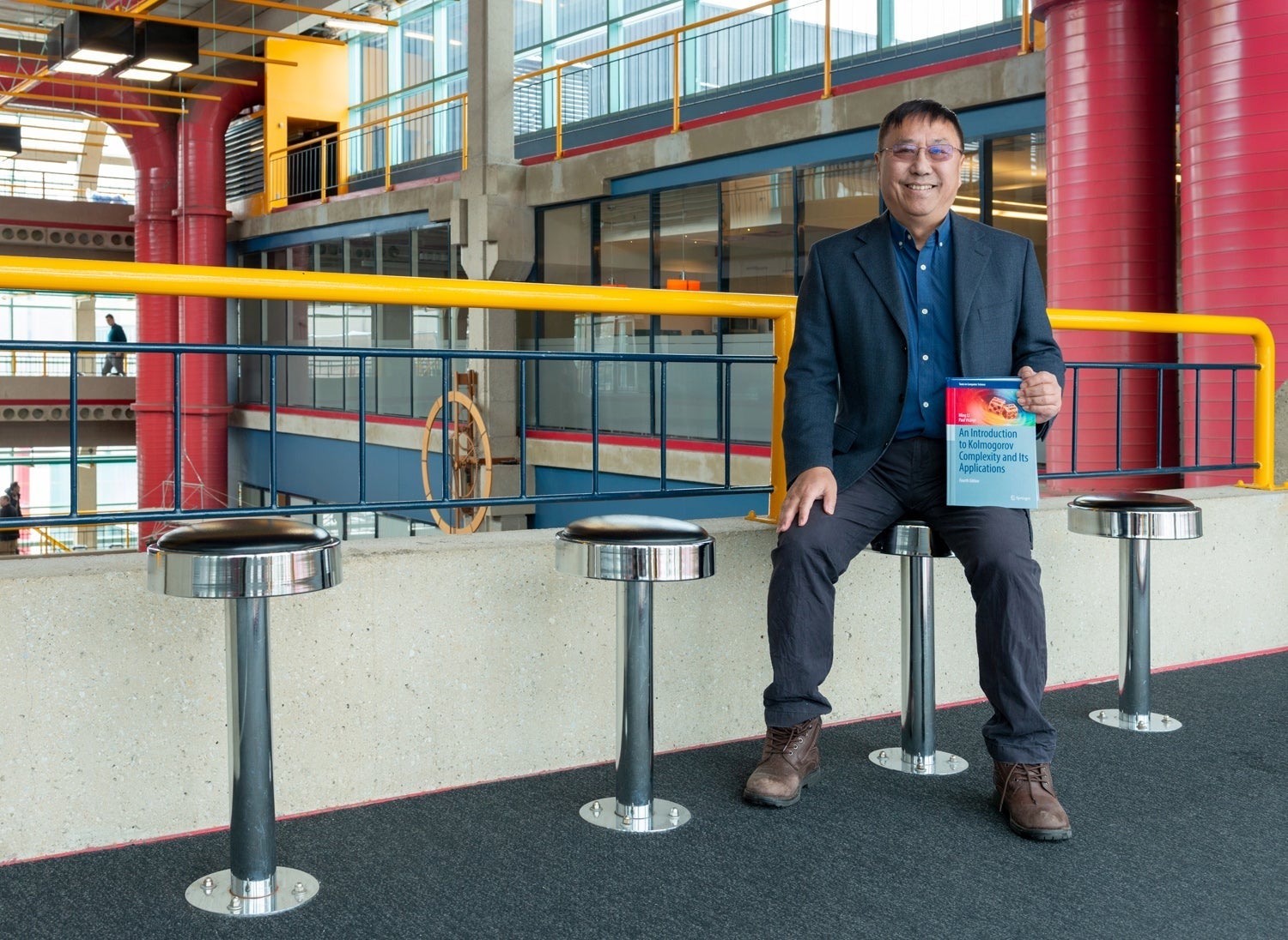 University Professor Ming Li in the Davis Centre with a textbook.