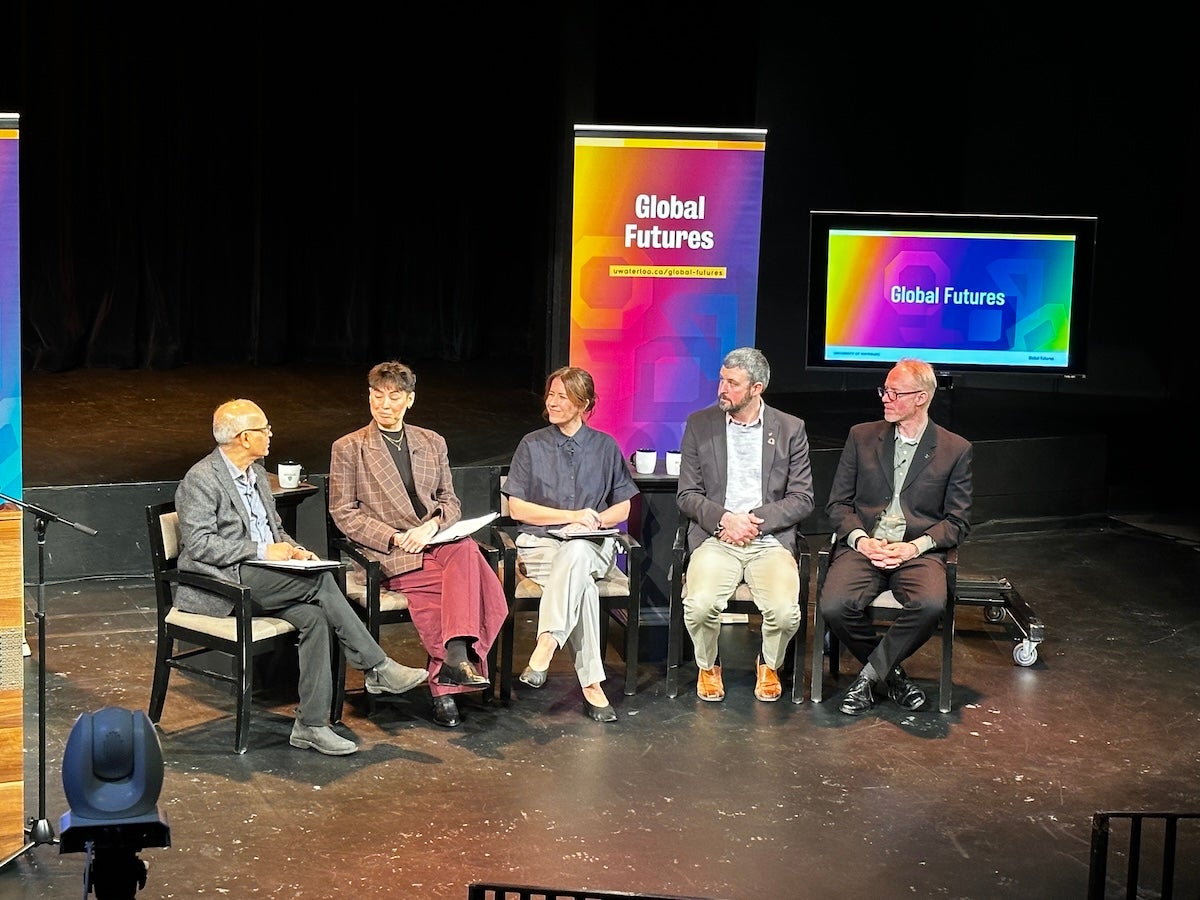 Vivek Goel moderates a panel discussion on stage.