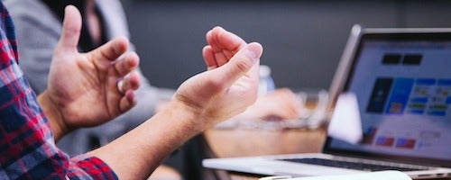 A person gestures while talking on a virtual laptop call.