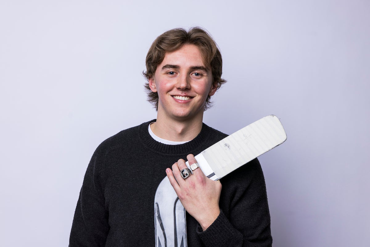 Mathias Onuska poses with a goalie stick and his Top 8 Academic All-Canadian ring.