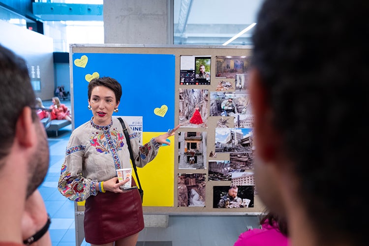 Halyna Padalko in front of a board full of photos.