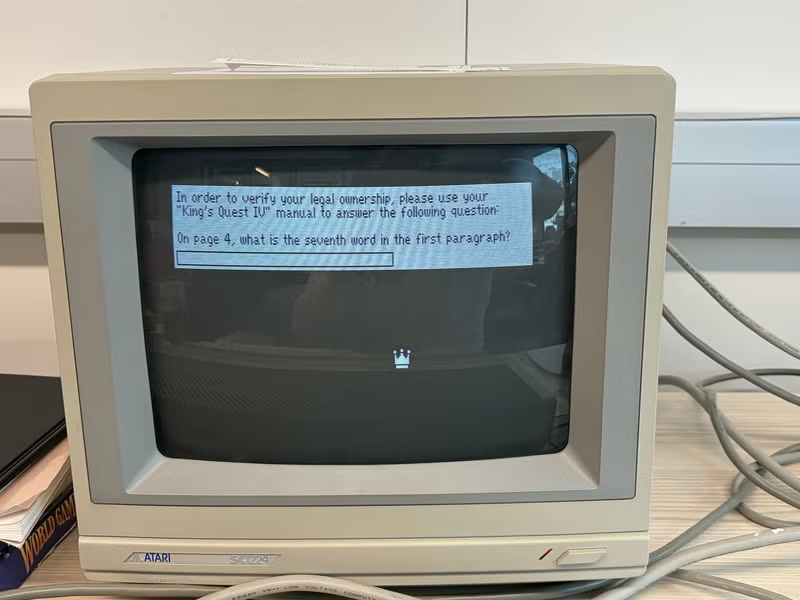 A computer monitor displays a prompt to type in a certain phrase from the game manual.