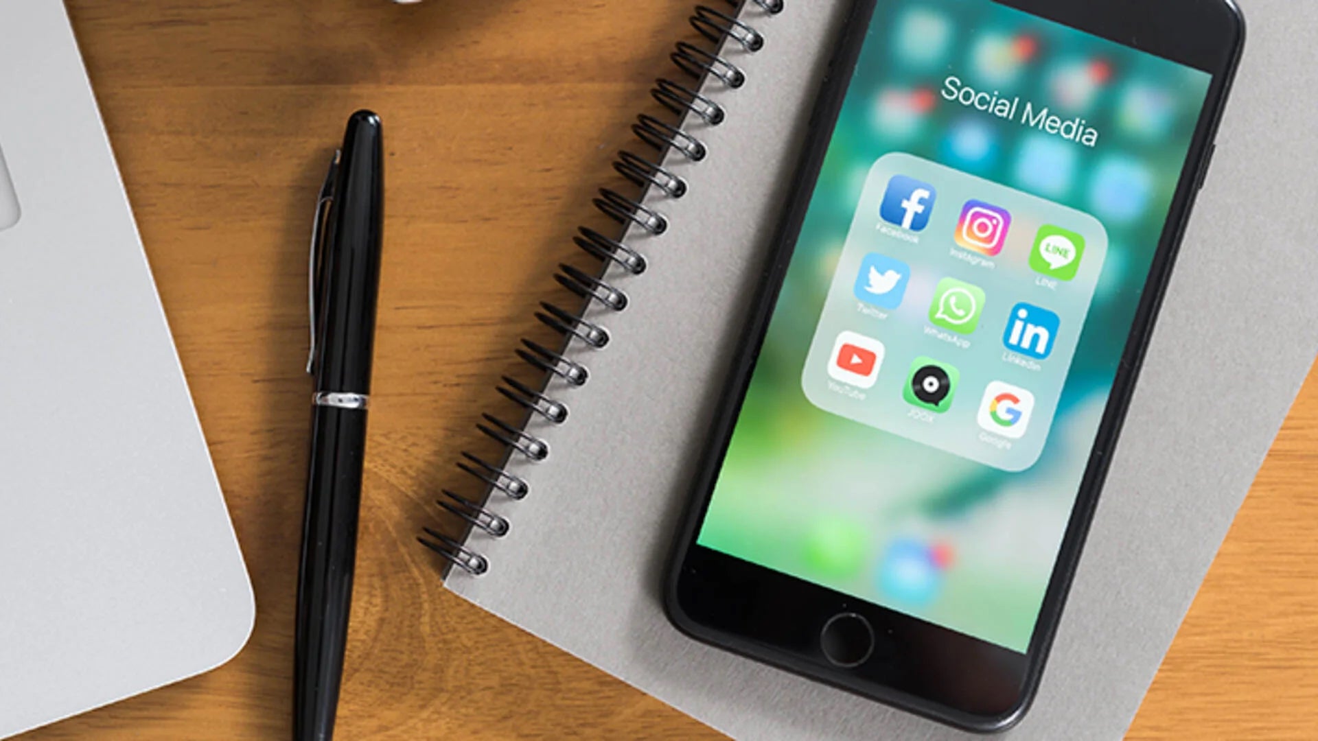 A smartphone rests atop a notebook.